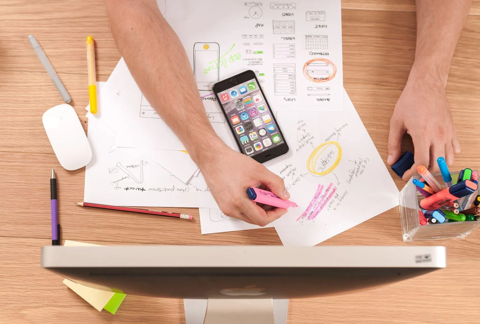 Arbeitsplatz mit Skizzen, Smartphone und Stiften, von oben gesehen