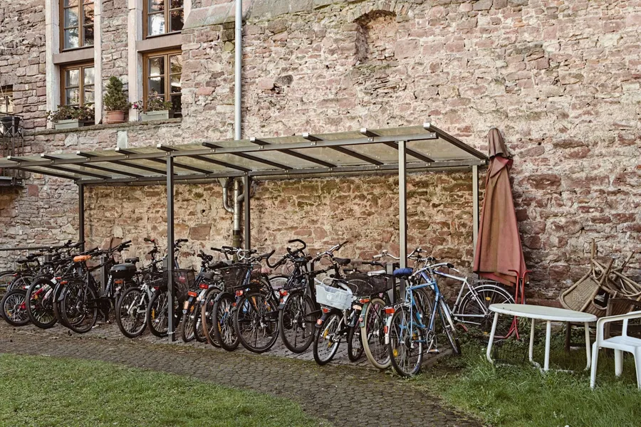 Fahrräder unter einem Unterstand vor einer historischen Mauer
